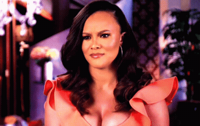 A Woman In A Red Dress With Ruffled Sleeves Is Making A Serious Face GIF