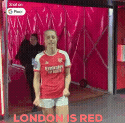 A Woman In A Red Emirates Jersey And Shorts Is Dancing GIF