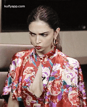 A Woman In A Red Floral Dress Is Sitting On A Couch . GIF