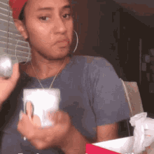 A Woman In A Red Hat Is Holding A Cup And A Ball In Her Hand . GIF