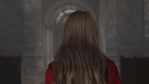 A Woman In A Red Jacket And Choker Looks At The Camera GIF