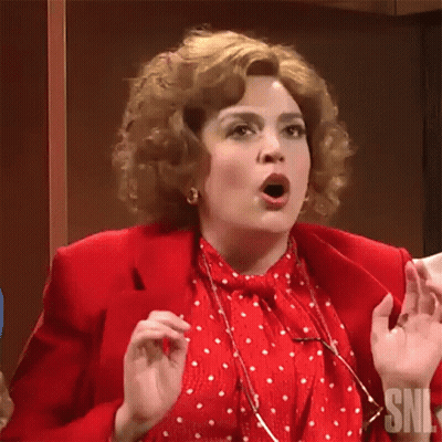 A Woman In A Red Jacket And White Polka Dot Shirt Is Making A Surprised Face . GIF