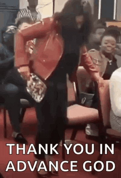 A Woman In A Red Jacket Is Dancing In Front Of A Crowd Of People While Sitting In Chairs . GIF