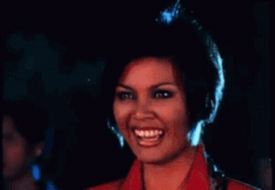 A Woman In A Red Jacket Is Laughing With Her Mouth Open . GIF