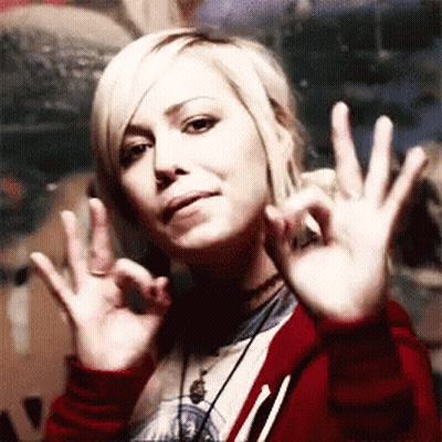 A Woman In A Red Jacket Is Making An Ok Sign With Her Hands GIF