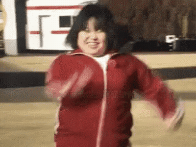 A Woman In A Red Jacket Is Smiling And Dancing . GIF