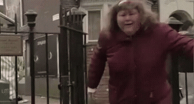 A Woman In A Red Jacket Is Standing In Front Of A Fence . GIF