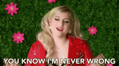 A Woman In A Red Jacket Is Standing In Front Of Pink Flowers . GIF