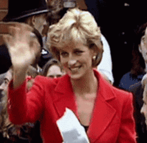 A Woman In A Red Jacket Is Waving At A Crowd GIF