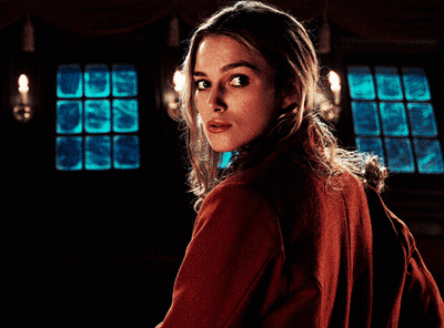 A Woman In A Red Jacket Looks Over Her Shoulder At The Camera GIF