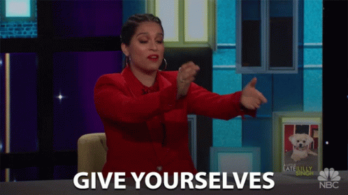 A Woman In A Red Jacket Says Give Yourselfs In Front Of A Picture Of A Dog GIF
