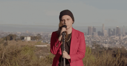 A Woman In A Red Jacket Sings Into A Microphone GIF