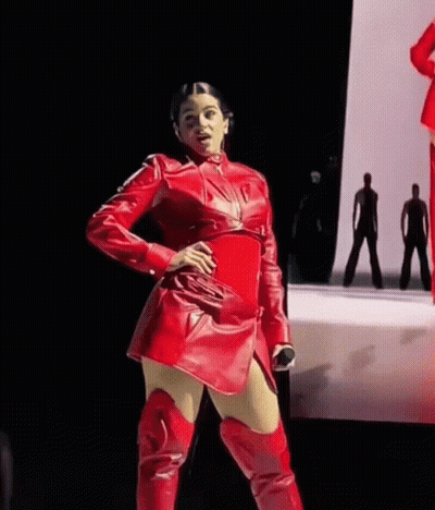 A Woman In A Red Leather Dress And Red Boots Is Standing On A Stage . GIF