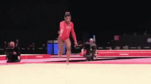 A Woman In A Red Leotard Is Doing A Routine On A Mat GIF