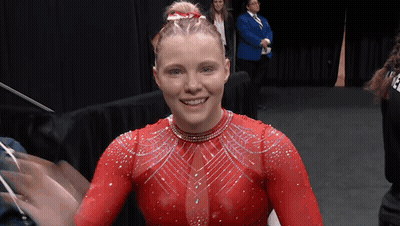 A Woman In A Red Leotard Is Smiling GIF
