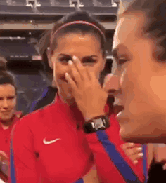 A Woman In A Red Nike Jacket Is Covering Her Face While A Man Looks On . GIF