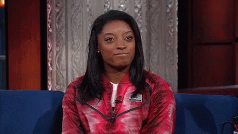 A Woman In A Red Nike Jacket Is Sitting On A Couch GIF