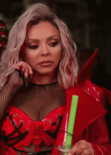 A Woman In A Red Outfit Is Holding A Green Object In Her Hand GIF