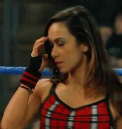 A Woman In A Red Plaid Top Is Standing In A Boxing Ring . GIF