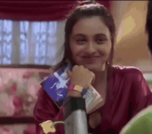 A Woman In A Red Robe Is Smiling While Holding A Piece Of Paper With A Star On It GIF