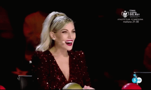 A Woman In A Red Sequined Dress Is Sitting In Front Of A Microphone With Her Hands In The Air . GIF