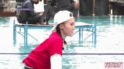 A Woman In A Red Shirt And White Hat Is Kneeling In A Pool With A Watermark That Says Neqt GIF