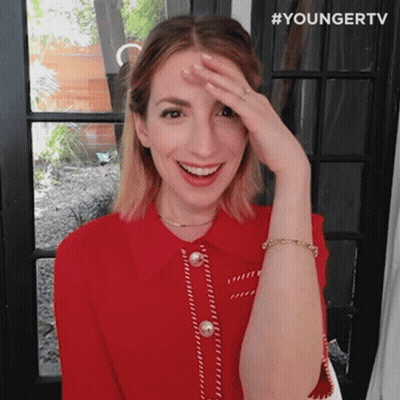 A Woman In A Red Shirt Is Covering Her Face With Her Hand And Smiling . GIF