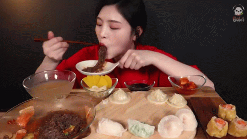 A Woman In A Red Shirt Is Eating A Bowl Of Soup With Chopsticks GIF