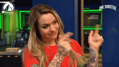 A Woman In A Red Shirt Is Giving A Thumbs Up In Front Of A Paramount Network Sign GIF