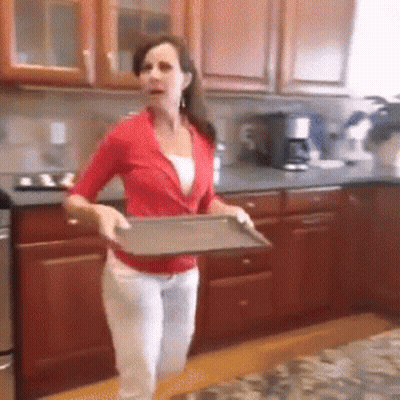 A Woman In A Red Shirt Is Holding A Metal Tray In A Kitchen GIF
