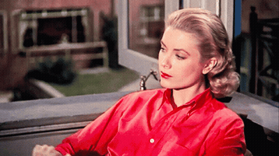 A Woman In A Red Shirt Is Looking Out Of A Window GIF