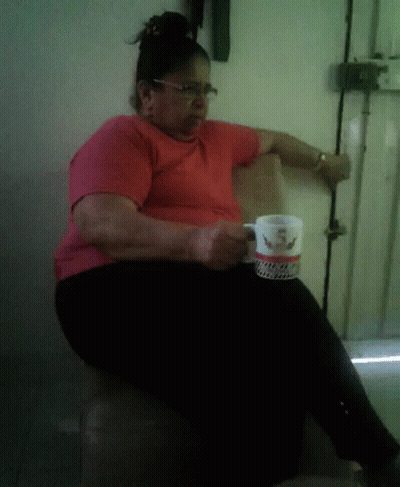 A Woman In A Red Shirt Is Sitting In A Chair Holding A Coffee Mug That Says ' I Love You ' On It GIF