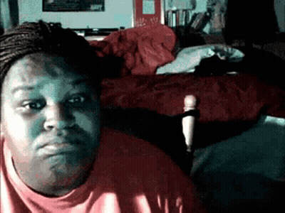 A Woman In A Red Shirt Is Sitting In Front Of A Bed With A Red Blanket On It GIF