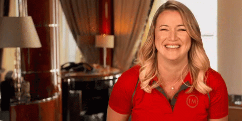 A Woman In A Red Shirt Is Smiling And Laughing In A Room . GIF