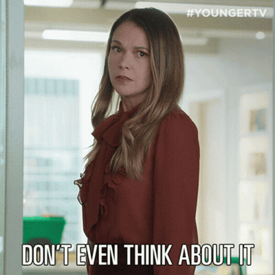 A Woman In A Red Shirt Is Standing In Front Of A Sign That Says " Do N't Even Think About It " GIF