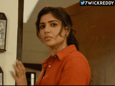 A Woman In A Red Shirt Is Standing In Front Of A Wall With A 7Wickreddy Logo Above Her GIF
