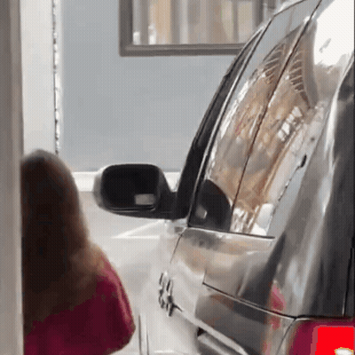 A Woman In A Red Shirt Is Standing Next To A Black Suv . GIF