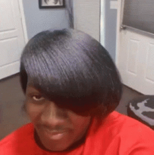 A Woman In A Red Shirt Is Taking A Selfie With Her Hair . GIF