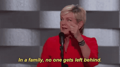 A Woman In A Red Shirt Is Talking Into A Microphone And Says In A Family No One Gets Left Behind GIF