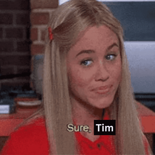 A Woman In A Red Shirt Says " Sure Tim " While Looking At The Camera GIF