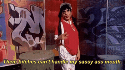 A Woman In A Red Shirt Says " Them Bitches Can 'T Handle My Sassy Ass Mouth " While Standing In Front Of Graffiti GIF