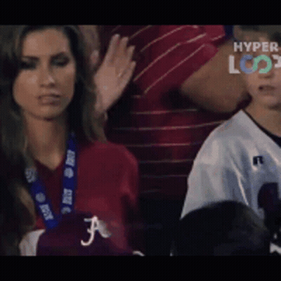 A Woman In A Red Shirt With The Letter F On It Looks At A Boy In A White Jersey GIF