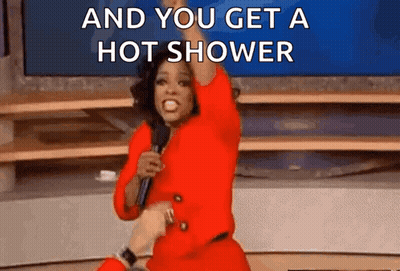 A Woman In A Red Suit Is Holding A Microphone And Saying `` And You Get A Hot Shower '' GIF