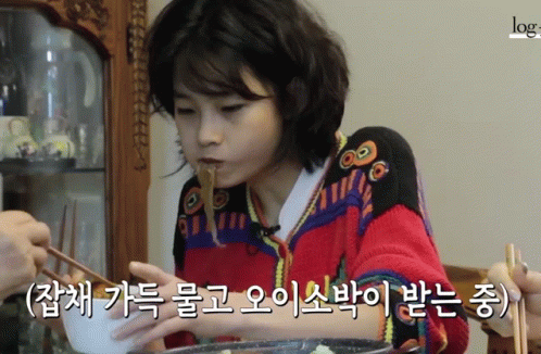 A Woman In A Red Sweater Is Eating Noodles With Chopsticks In A Video That Says Log GIF