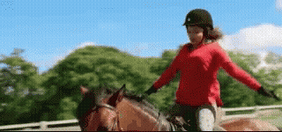 A Woman In A Red Sweater Is Riding A Brown Horse In A Fenced In Area . GIF