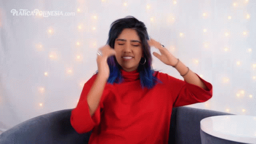 A Woman In A Red Sweater Is Sitting In Front Of A Sign That Says Platform Indonesia.com GIF