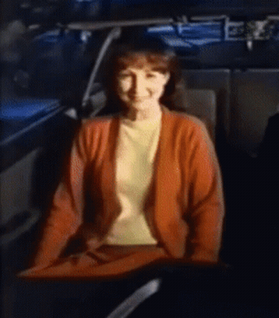 A Woman In A Red Sweater Is Sitting In The Back Seat Of A Car GIF