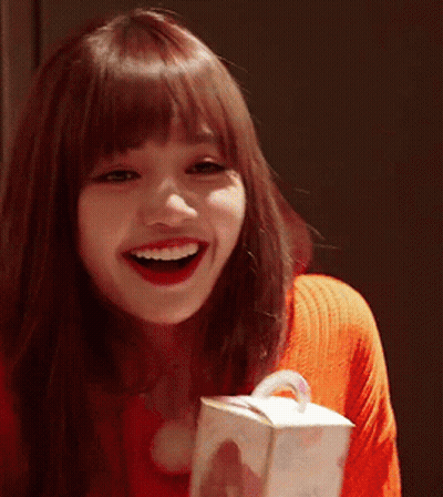 A Woman In A Red Sweater Is Smiling While Holding A Box GIF