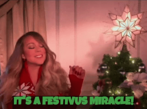 A Woman In A Red Sweater Is Standing In Front Of A Christmas Tree And A Star . GIF