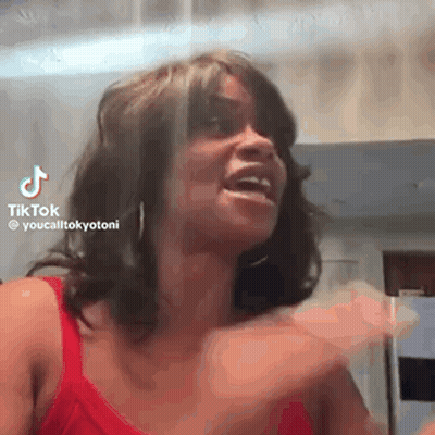 A Woman In A Red Tank Top Is Making A Funny Face And Laughing . GIF